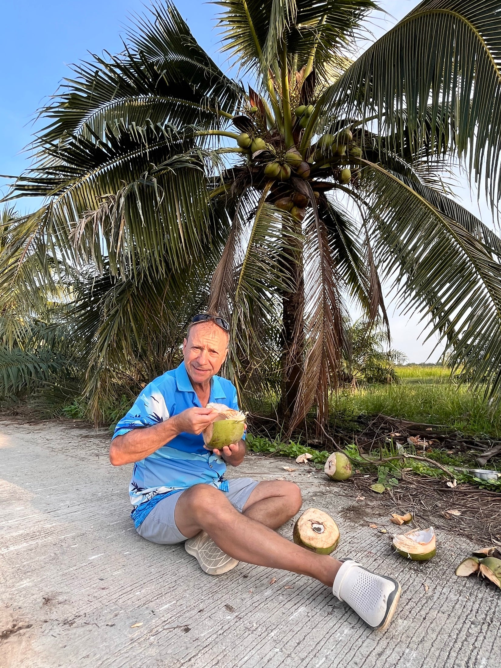 Jim enjoying a fresh coconut beside a palm grove in Southern Thailand